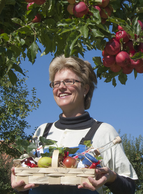 Heidi Kocher mit individuellen regionalen Geschenken unter traditionellem Hochstamm-Apfelbaum